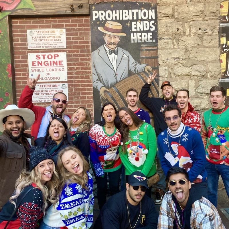 Tacky Sweater Crawl Participants Posing For Group Photo In Printers Alley