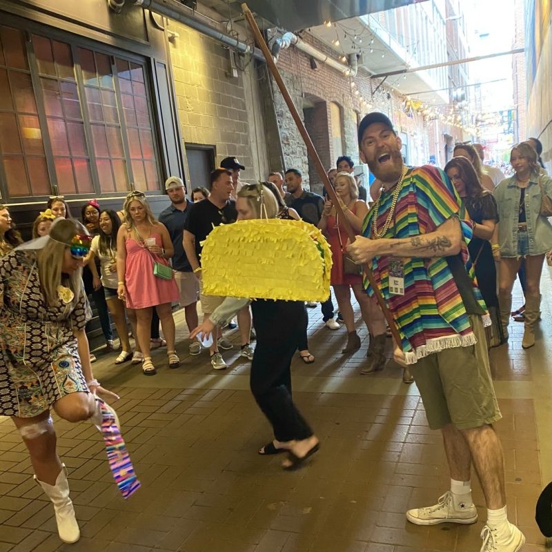 Tour Guide Wearing Mexican Poncho And Holding Taco Piñata